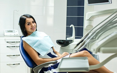 A young woman smiling while seated in the dentist’s chair