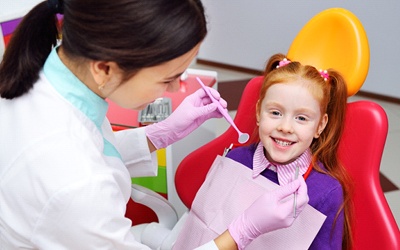 A little girl with red hair smiling as she sees a dentist offering children’s dentistry in Allen