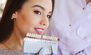 woman's smile compared with tooth color chart