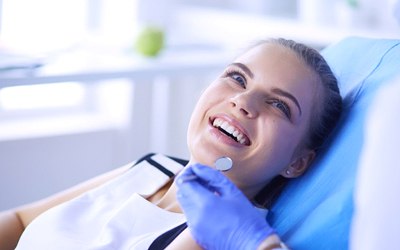 A young woman is good oral health smiling at her dentist in preparation for a checkup