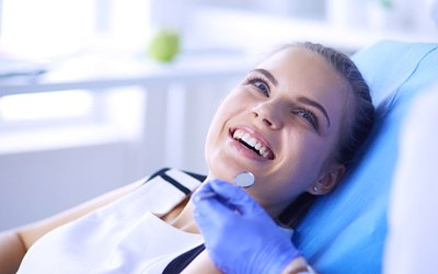 A young woman is good oral health smiling at her dentist in preparation for a checkup