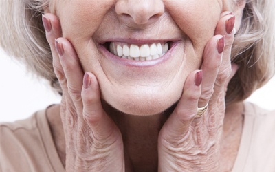 An older woman holding her face and smiling