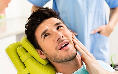 Man in dental chair holding cheek